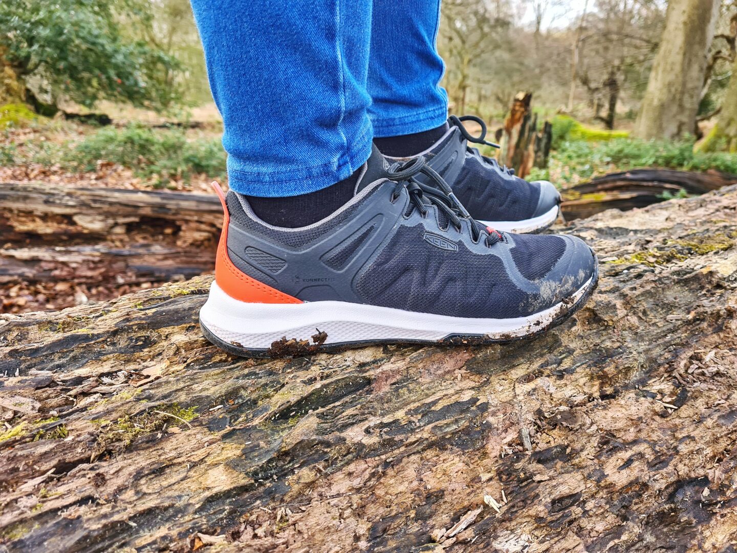 Close up of feet wearing Keen walking shoes standing on a fallen log