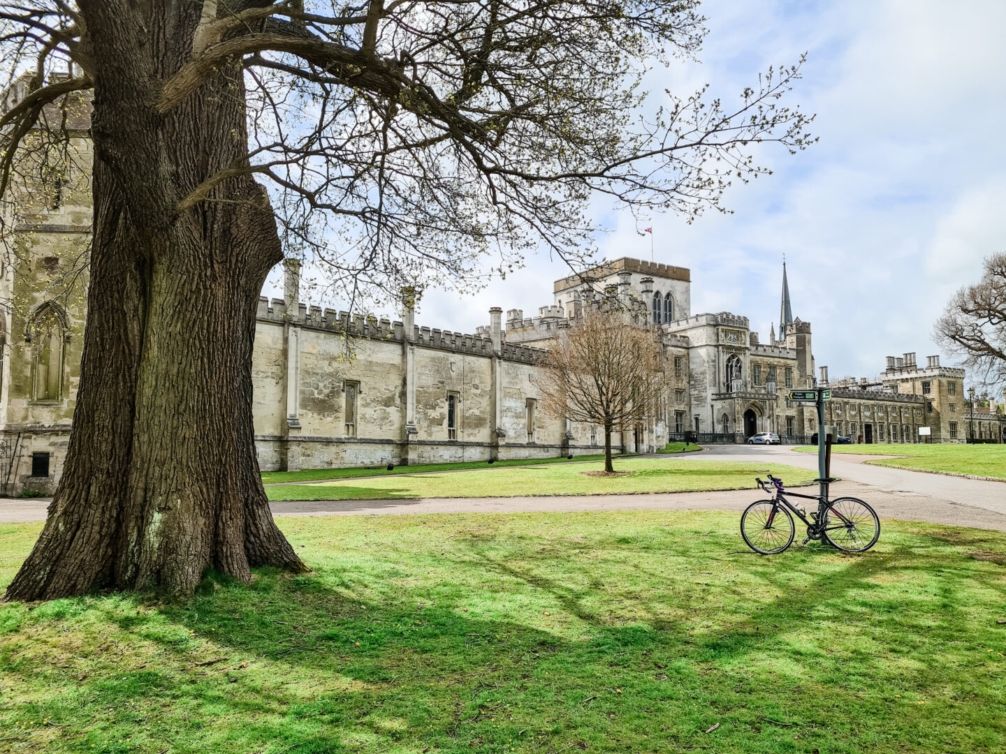 A road bike leans up against a road sign with Ashridge College, an imposing building in the background. 