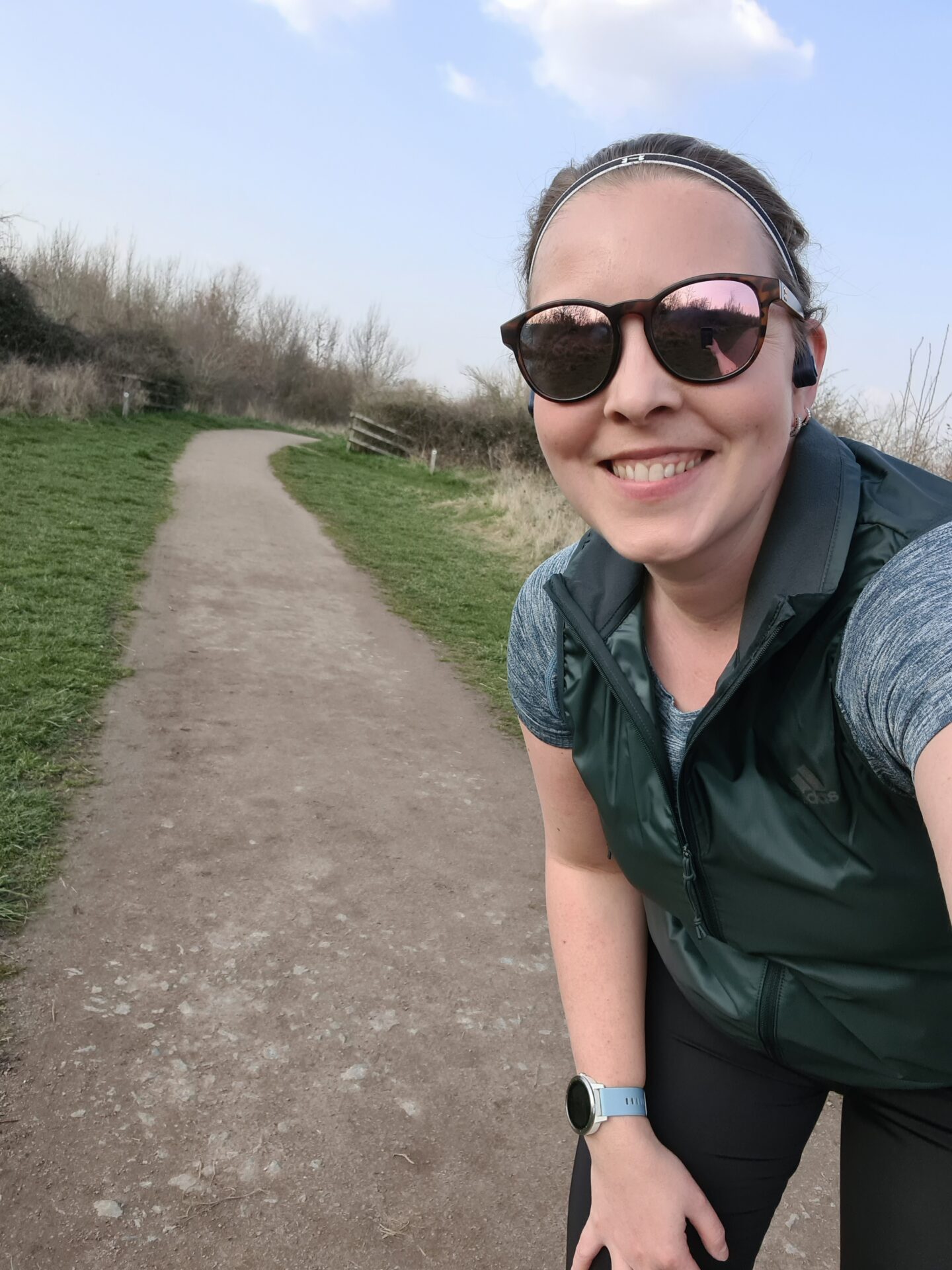 Selfie of woman wearing green running gilet and sunglasses. 