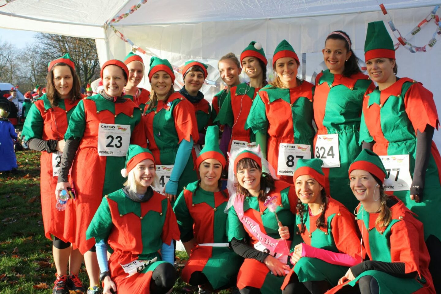 Group of female runners dressed in red and green elf outfits pose for a group photo