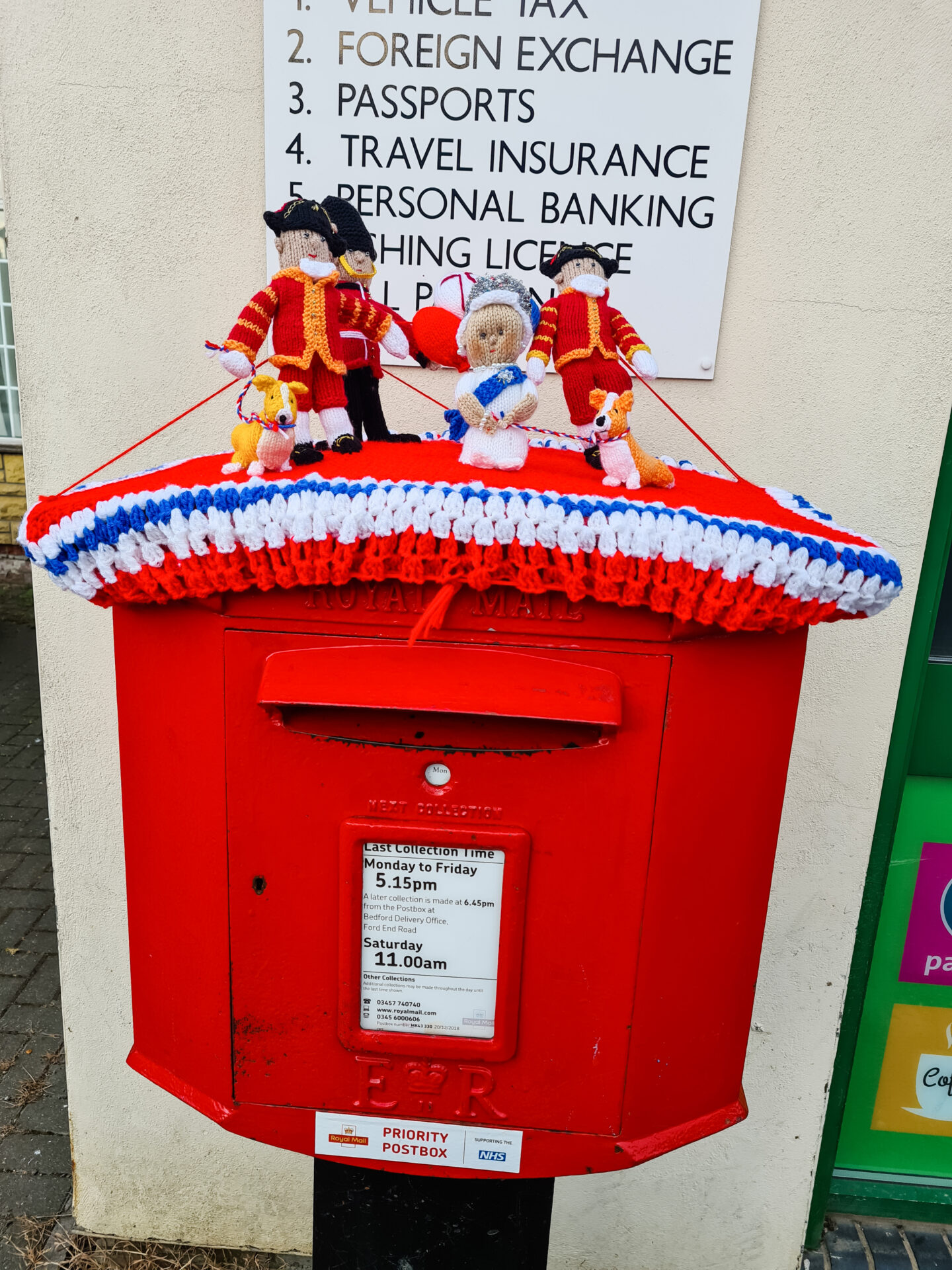 A red postbox with crocheted Queen and other royal figures on top