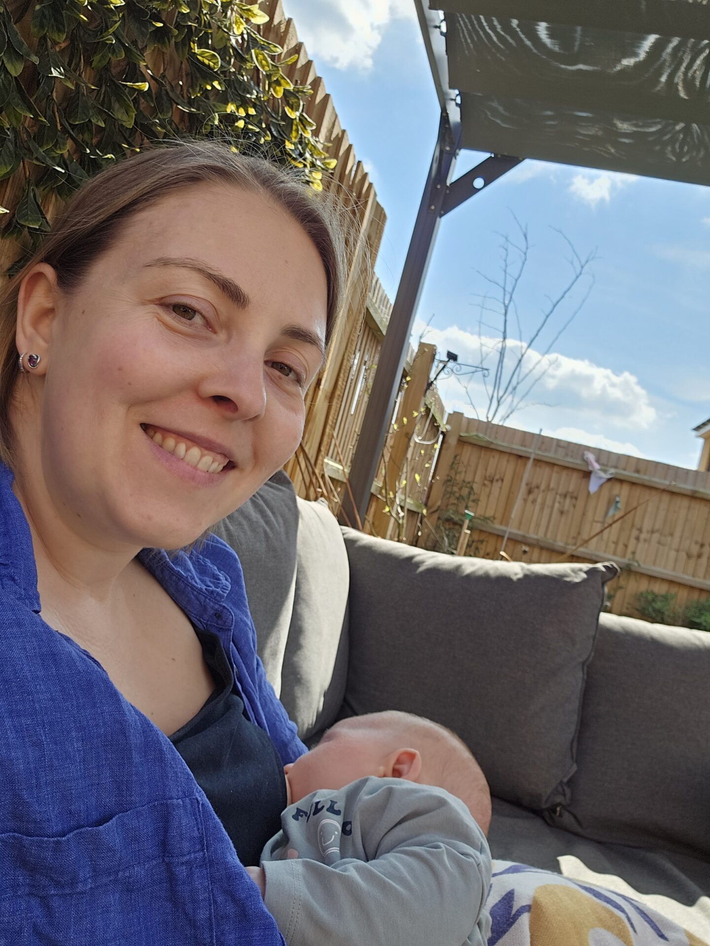 woman sitting on a garden sofa breastfeeding a small baby 