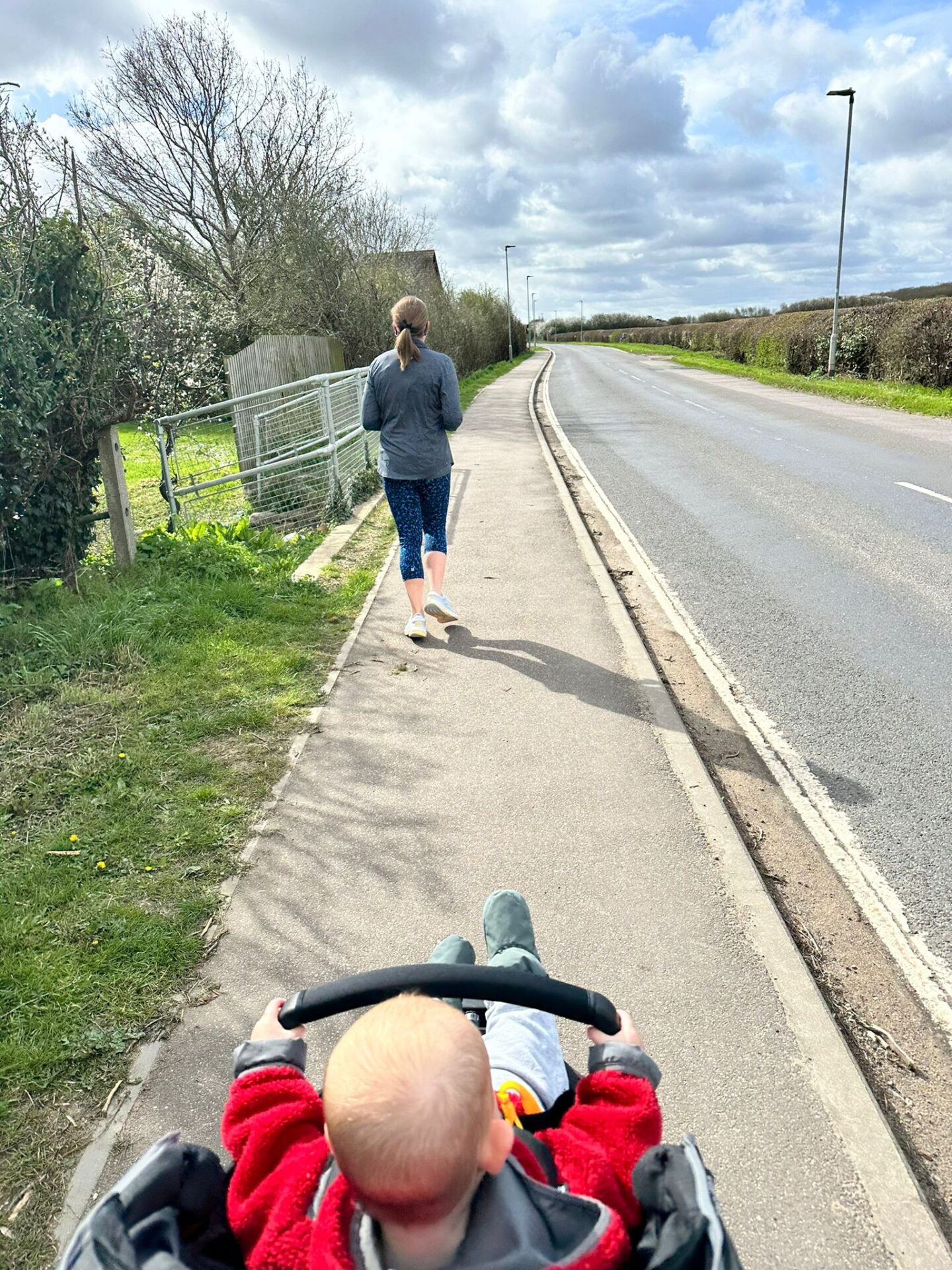 Back of a female runner on the pavement with close up shot over baby's head in the pushchair